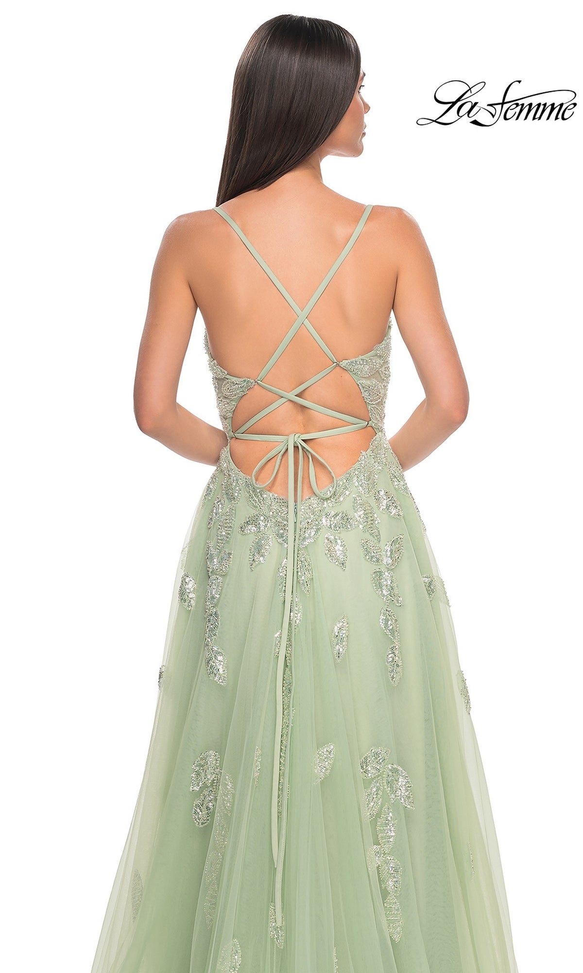 Woman in the La Femme Sequin-Embroidered Long Prom Dress 32090, a light green A-line gown with sequin embroidery and crisscross lace-up back straps, is shown from behind.